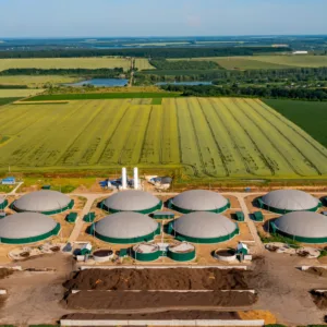 Biogasanlage mit mehreren großen, runden Biogastanks in einem grünen, landwirtschaftlichen Gebiet.